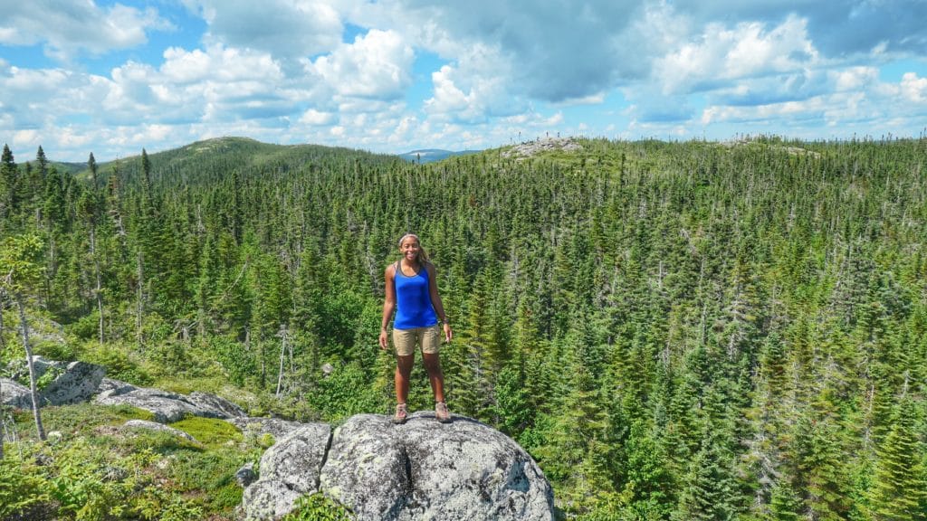 Maeva du blog de Partir Loin debout sur une roche avec une forêt dense derrière elle