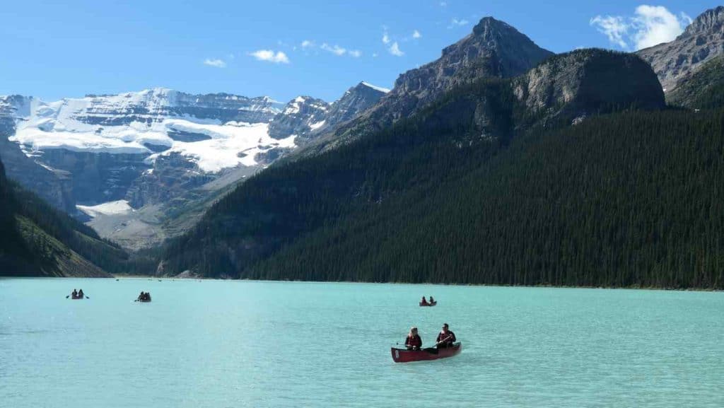 vue sur le lac louise avec les montagnes en arrière plan et les petits canoé sur le lac